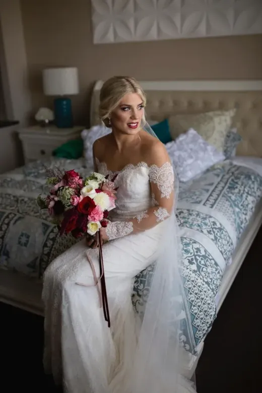 Bride with a bouquet in a lace gown in a getting-ready suite